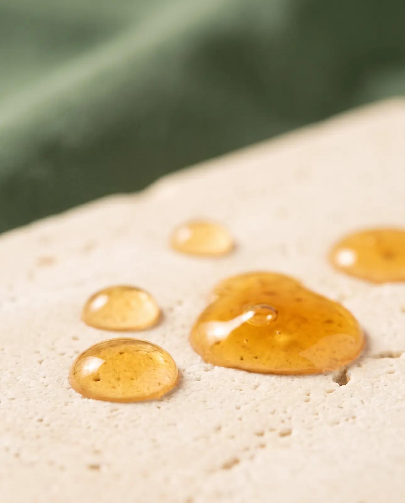 Golden drops of liquid collagen on a stone surface